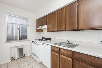 Denver apartment for rent - A kitchen with white appliances and brown cabinets.