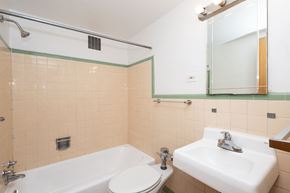 Denver apartment for rent - A white sink is in a bathroom with a white tub and toilet.