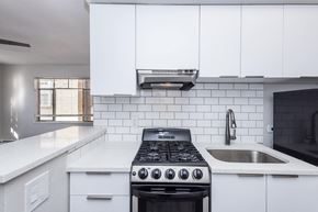 Denver apartment for rent - A modern kitchen with a black stove top oven and white cabinets.