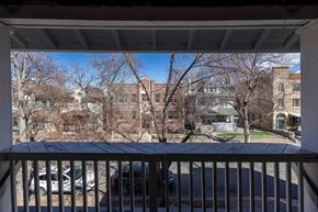 Denver apartment for rent - A view from a balcony overlooking a parking lot and apartment buildings.