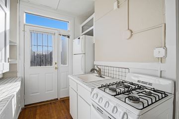 Denver apartment for rent - A white kitchen with a gas stove and a window.