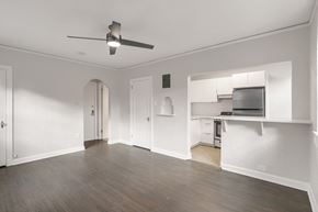 Denver apartment for rent - A room with a ceiling fan and a kitchen area in the background.
