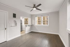 Denver apartment for rent - A room with a ceiling fan and a window with bars.