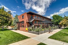 Denver apartment for rent - A red brick building with a black fence in front.
