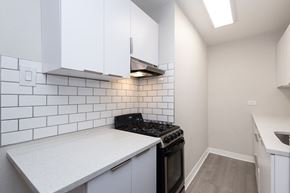 Denver apartment for rent - A kitchen with white cabinets and a black stove top oven.