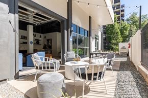 Denver apartment for rent - a patio with white chairs and tables and a building with glass doors