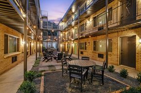 Denver apartment for rent - A patio with a table and chairs is surrounded by brick buildings.