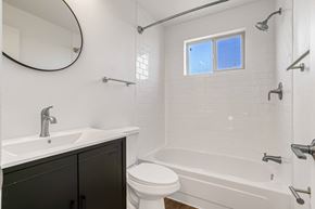 Denver apartment for rent - A white bathroom with a black cabinet and a window.