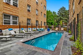 Denver apartment for rent - A pool surrounded by chairs and a brick building.