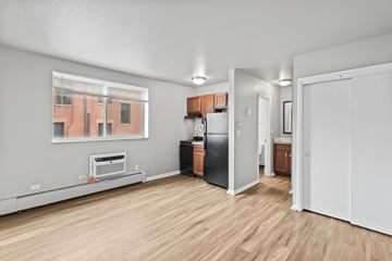 Denver apartment for rent - A kitchen with a black fridge and wooden floors.
