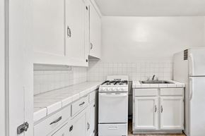 Denver apartment for rent - A white kitchen with a stove, sink, and refrigerator.