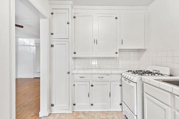 Denver apartment for rent - A kitchen with white cabinets and a white stove.