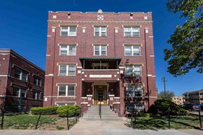 Denver apartment for rent - A red brick building with a green roof and a white door.