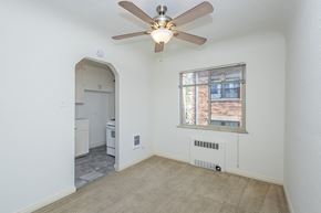 Denver apartment for rent - A room with a ceiling fan and a window with a view of a brick building outside.