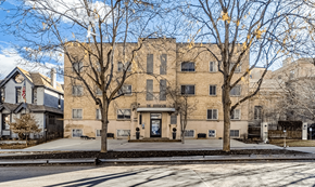 Denver apartment for rent - A large building with a flag on the left side and a tree in front of it.