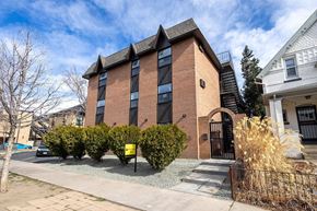 Denver apartment for rent - A red brick building with a black gate in front.