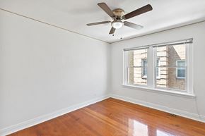 Denver apartment for rent - A room with a ceiling fan and a window showing a view of a building outside.