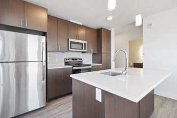 Denver apartment for rent - a modern kitchen with stainless steel appliances and a white counter top