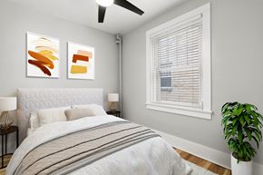 Denver apartment for rent - A bedroom with a bed, two lamps, a plant, and two paintings on the wall.