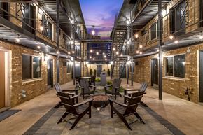 Denver apartment for rent - A patio with a table and chairs is surrounded by brick buildings.