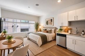 Denver apartment for rent - A modern bedroom with a large bed, a kitchenette, and a dining area.