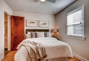 Denver apartment for rent - A bedroom with a large bed and a wooden door.