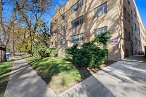 Denver apartment for rent - A tall brick building with a green bush in front of it.