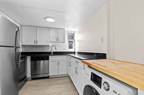 Denver apartment for rent - a kitchen with white cabinets and stainless steel appliances and a wood counter top