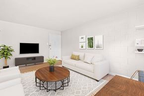 Denver apartment for rent - A living room with a white couch, a brown coffee table, and a flat screen TV.