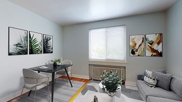 Denver apartment for rent - A living room with a grey couch, a dining table with chairs, and three framed pictures on the wall.