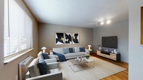 Denver apartment for rent - A living room with a grey couch, a coffee table, and a television.