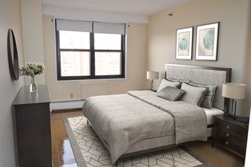 Cambridge apartment for rent - A bedroom with a large bed and a vase of flowers on a nightstand.