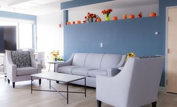 Medford apartment for rent - A living room with a grey sofa, a grey armchair, and a small table with flowers.