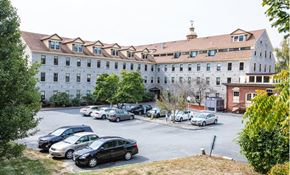 Whitinsville apartment for rent - a parking lot with cars in front of a large building