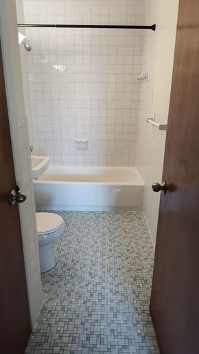 Boston apartment for rent - A white toilet is in a bathroom with a white tub and a tile floor.