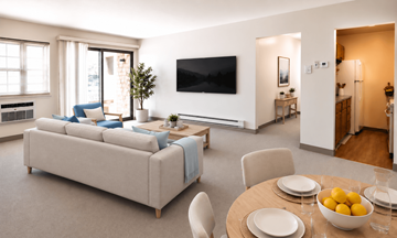 Attleboro apartment for rent - A living room with a couch, a television, and a dining table set for two.