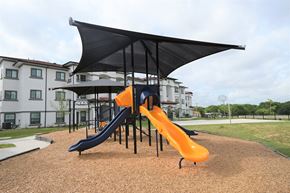 San Antonio apartment for rent - a playground with a slide and umbrella in front of a building
