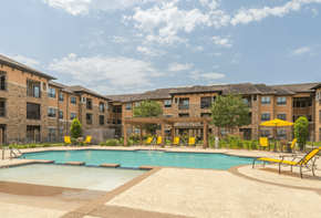 Cypress apartment for rent - A swimming pool surrounded by yellow chairs and apartment buildings.