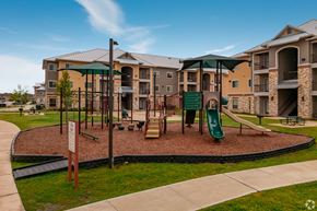San Antonio apartment for rent - A playground area with a green slide and a brown sandbox in front of apartment buildings.