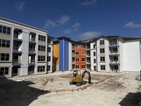 San Antonio apartment for rent - a bulldozer sits in the middle of a construction site next to an apartment building