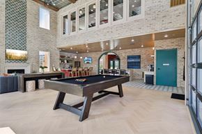 Liberty Township townhouse for rent - A pool table in the resident lounge with a brick wall and a fireplace.