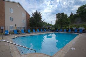 Southgate apartment for rent - A large swimming pool surrounded by a metal fence and blue lounge chairs.