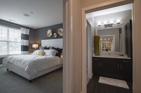 West Chester apartment for rent - A bedroom with a large bed and a bathroom with a mirror and sink.