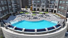 Cincinnati apartment for rent - A round swimming pool surrounded by a stone patio and lounge chairs.