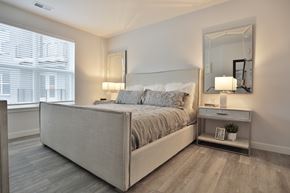 Cincinnati apartment for rent - A bedroom with a large bed and a nightstand with a mirror above it.