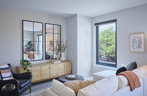 Chicago apartment for rent - A living room with a white couch, a black chair, and a wooden cabinet with a mirror above it.
