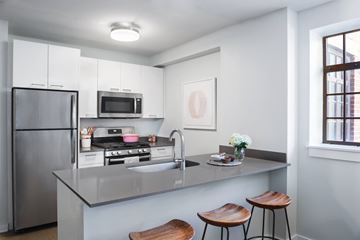Chicago apartment for rent - A modern kitchen with a stainless steel refrigerator, microwave, and a sink with a faucet.