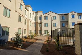 Las Vegas apartment for rent - A row of modern apartment buildings with a black fence in the foreground.