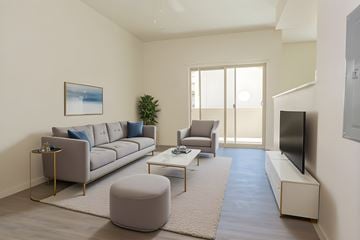 Las Vegas apartment for rent - A living room with a grey sofa, a grey armchair, a grey ottoman, a coffee table, a flat screen TV, and a painting on the wall.