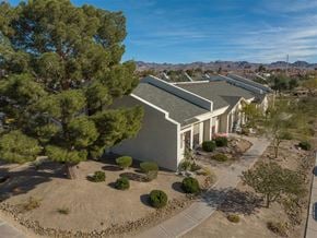 Henderson apartment for rent - A house with a grey roof and white walls is surrounded by a garden with a large tree.